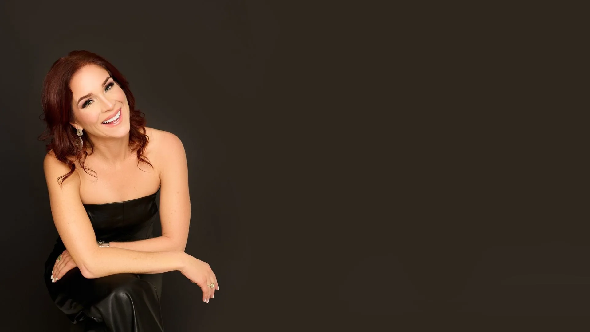 Stacey Vanthuyne laughing, seated in a black dress